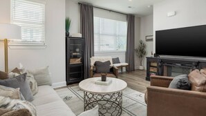 Uma sala de estar moderna com sofá, mesa de centro e televisão.