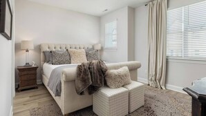 Quarto com cama, mesa de cabeceira, abajur e ventoinha no teto.