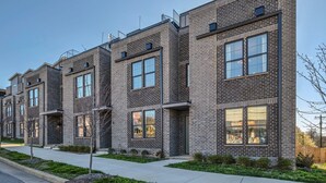 A row of modern brick townhouses with large windows, a sidewalk, and small trees. - NEW!  Sleek Rooftop Retreat - Sleeps 10 (Nashville)