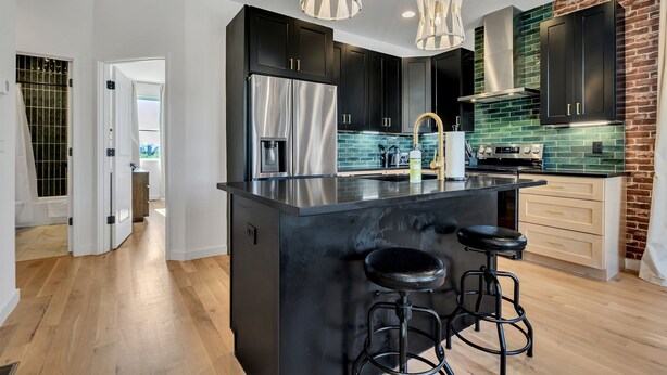 A modern kitchen with black cabinets, stainless steel appliances, and a central island with stools. - NEW!  Sleek Rooftop Retreat - Sleeps 10 (Nashville)