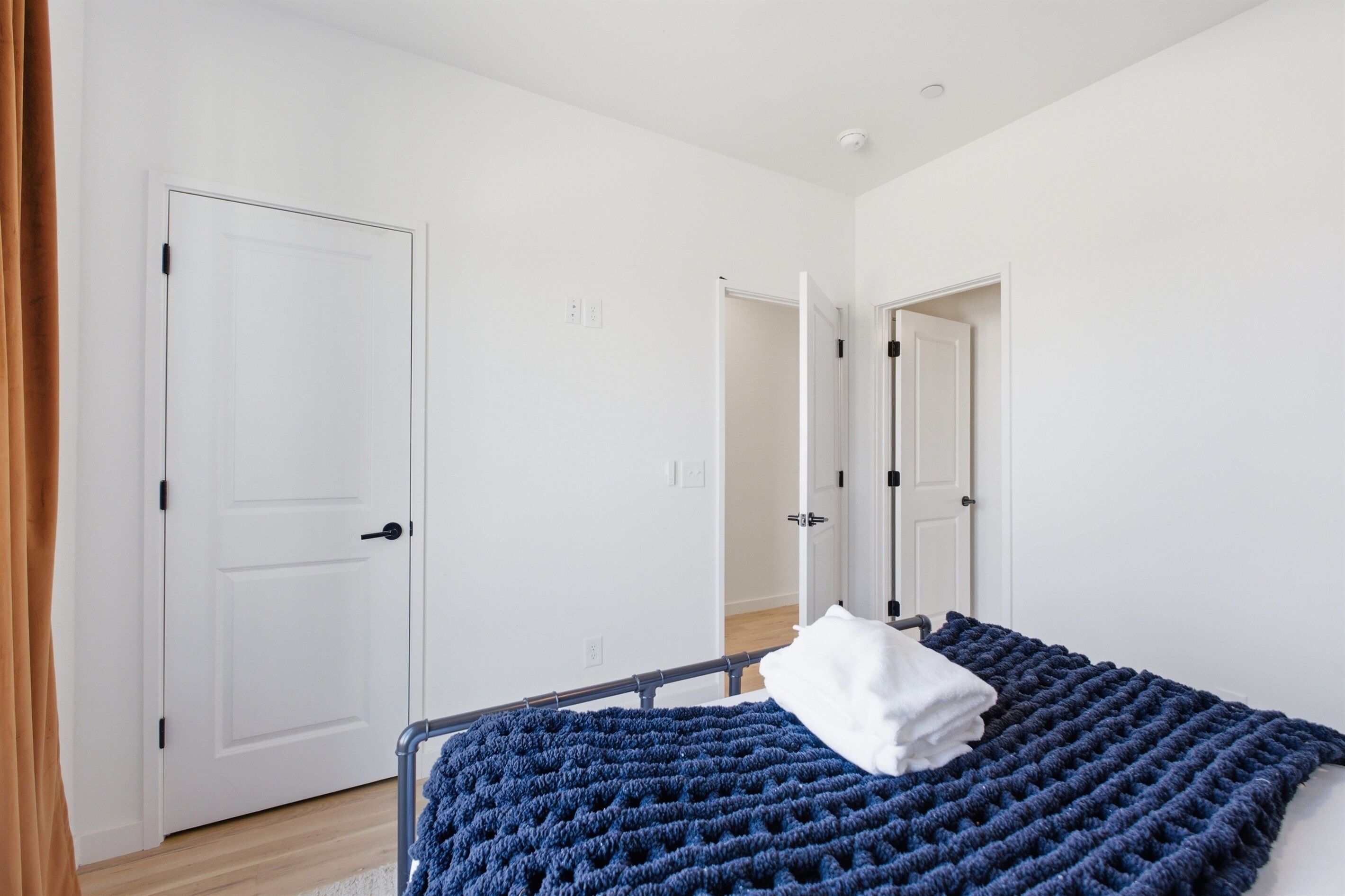 Une chambre à coucher avec un lit, des murs blancs et une porte.