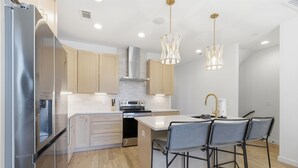 A modern kitchen with stainless steel appliances, wooden cabinets, and a central island with bar stools.