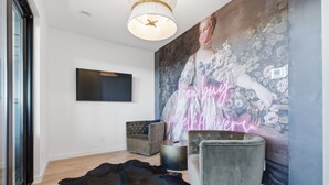 A modern living room with a flat-screen TV, a large floral mural, and a plush sofa.