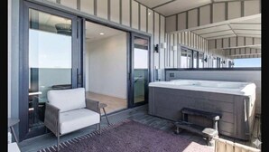 En modern inredning med en soffa, ett bubbelbad och en glasdörr som leder ut till ett utomhusområde.
