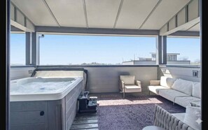 Un bain à remous, un canapé et un fauteuil dans une pièce baignée de lumière, avec de grandes fenêtres.