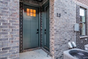 A building with a green door, brick walls, and a window with a number '13' on the right side.