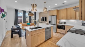 A modern kitchen with a central island, stainless steel appliances, and wooden cabinets. - Rooftop Views + Relaxing Hot Tub & Fire Pit (Nashville)