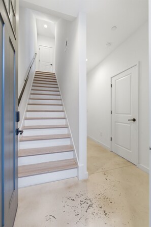 Una escalera que lleva a una puerta, una pared blanca y un suelo con algunas marcas.
