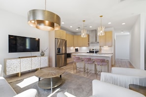 Uma cozinha moderna com eletrodomésticos de aço inoxidável, uma ilha central com banquetas e iluminação pendente.