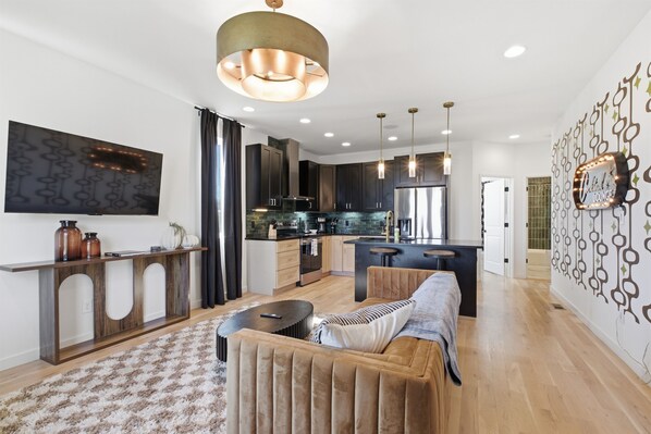 A modern kitchen with dark cabinets, a central island, and pendant lighting.
