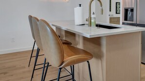 Una cucina moderna con isola centrale, lampade a sospensione e insegna luminosa al neon.