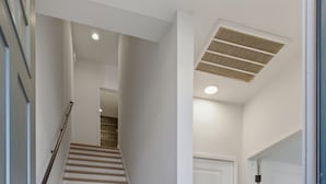 Una escalera conduce a un rellano con una puerta, una rejilla de ventilación en el techo y un suelo limpio.
