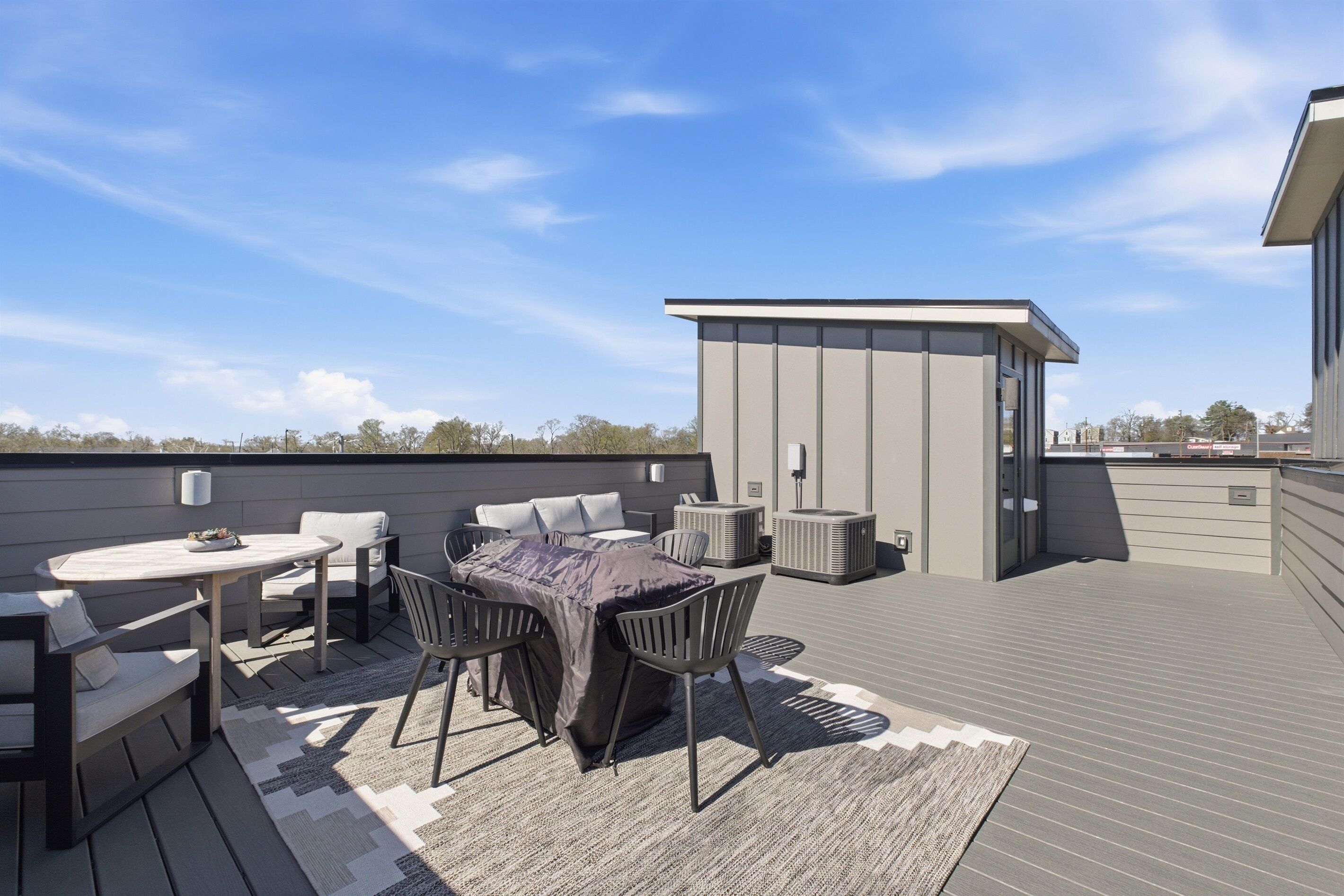 En takterrass med ett bord och stolar, en överbyggd sittplats och en liten, avskärmad konstruktion.