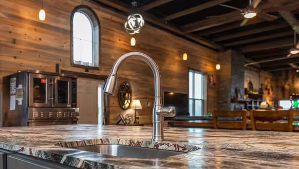 Une cuisine dotée d’un grand îlot central, d’appareils électroménagers en acier inoxydable et de murs en bois.