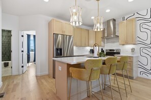 Une cuisine moderne dotée d’appareils électroménagers en acier inoxydable, de meubles en bois et d’un îlot central avec des tabourets de bar.