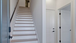 Eine Treppe führt zu einer Zwischenebene, mit einer Tür rechts und einer Tür links.