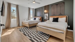 A modern bedroom with two beds, a ceiling fan, and artwork on the walls.