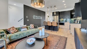 A modern living room with a green sofa, a coffee table, and a kitchen in the background.
