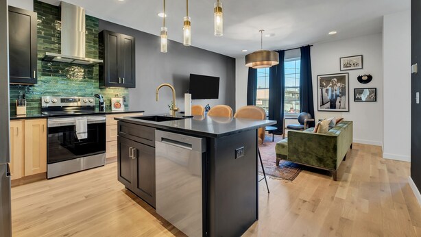 A modern kitchen with a central island, stainless steel appliances, and pendant lighting.