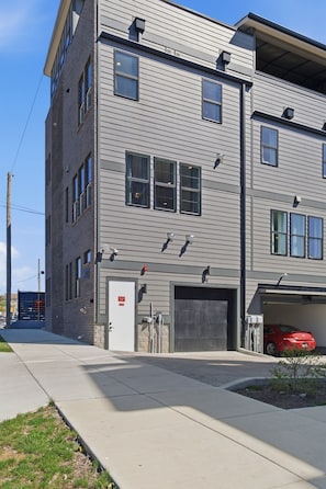 A multi-story building with a garage and a red car parked inside.