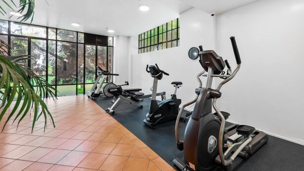 Une salle de sport équipée de vélos d’appartement, d’un tapis de course et d’un rameur.