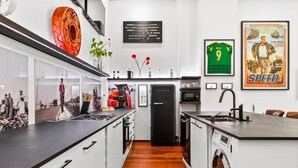 Une cuisine moderne avec un réfrigérateur noir, des meubles blancs et un plancher en bois.