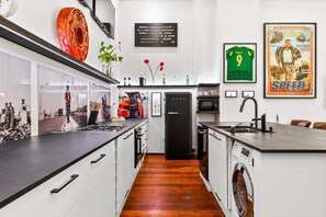Een moderne keuken met een zwarte koelkast, witte kastjes en een houten vloer.