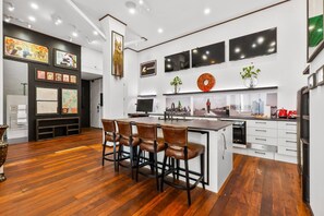 Een moderne keuken met een centraal eiland, barkrukken en een eethoek.