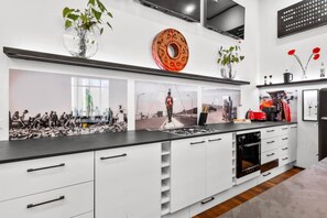 Een moderne keuken met witte kastjes, een zwart aanrecht en een groot raam.