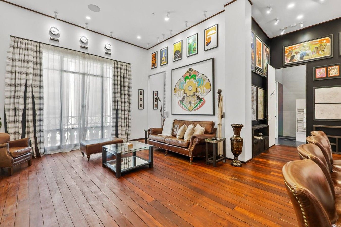 A spacious living room with a sofa, coffee table, and leather chairs.