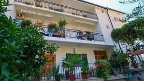A two-story building with balconies, potted plants, and outdoor furniture. - 1 bedroom awesome apartment in Gradac (Gradac)