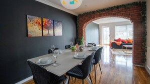 A dining area with a brick archway, a table set with plates and glasses, and a sofa in the background. - The Laurels - HS2 Contractors, NEC, BHX Airport Stays, Sleeps 12, Free Parking (Birmingham)
