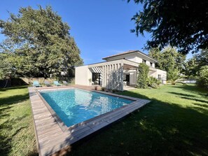 A modern house with a swimming pool, a patio, and a garden.
