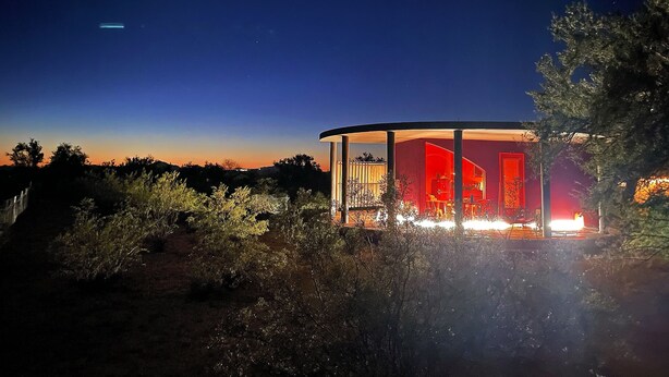 Un edificio circolare con facciata rossa e diverse finestre, immerso nel verde.