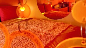Una stanza con un letto, uno specchio rotondo e una lampada.