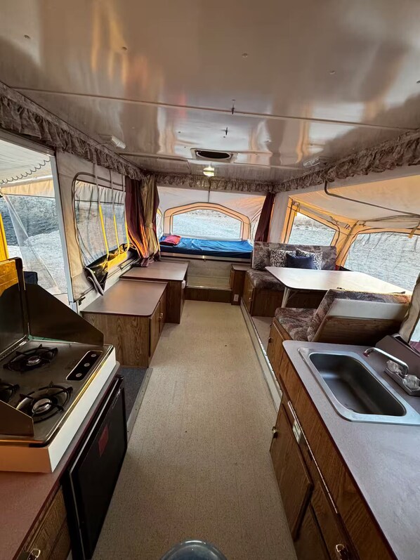 A compact RV interior with a kitchenette, a small dining area, and a sleeping berth. - Tranquil RV in San Juanico - 3 Bedrooms (San Juanico)