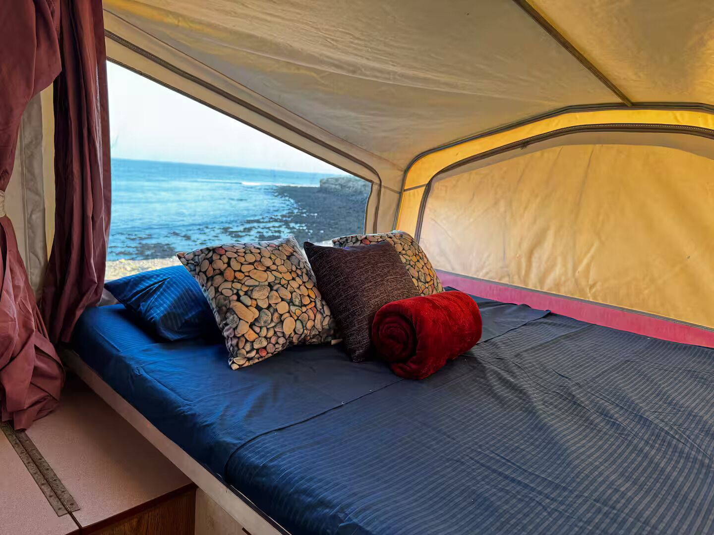 Una carpa con cama, almohadas y vista al océano.