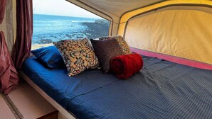 A tent with a bed, pillows, and a view of the ocean. - Tranquil RV in San Juanico - 3 Bedrooms (San Juanico)