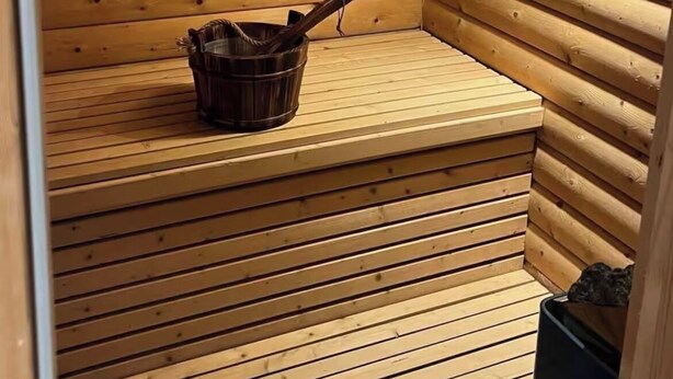 A wooden sauna with a bench and a bucket.