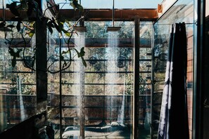 A room with a large window, a bed, and a shower area. - Grand Designs "Eco Bush Retreat" (Callignee)