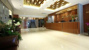 Zona de recepción de hotel con un mostrador de madera, una caja registradora y un cartel para el mostrador de información.