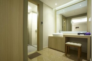 A modern bathroom with a large mirror, a sink, and a bench.