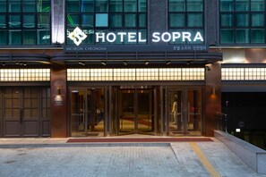 The entrance of Hotel Sopra with a modern design, featuring large glass doors and a clear view into the lobby.