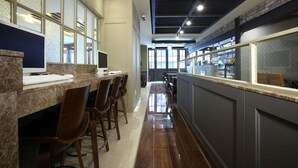 Zona de bar moderna con una barra larga, taburetes y vista a la cocina al fondo.