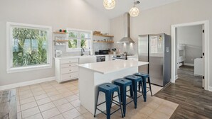 A modern kitchen with a large island, bar stools, and pendant lighting. - Oceanfront Family Retreat with Kids' Amenities & Stunning Views (Folly Beach)