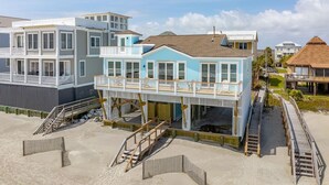 A beachfront property with a two-story house featuring a balcony and a deck. - Oceanfront Family Retreat with Kids' Amenities & Stunning Views (Folly Beach)