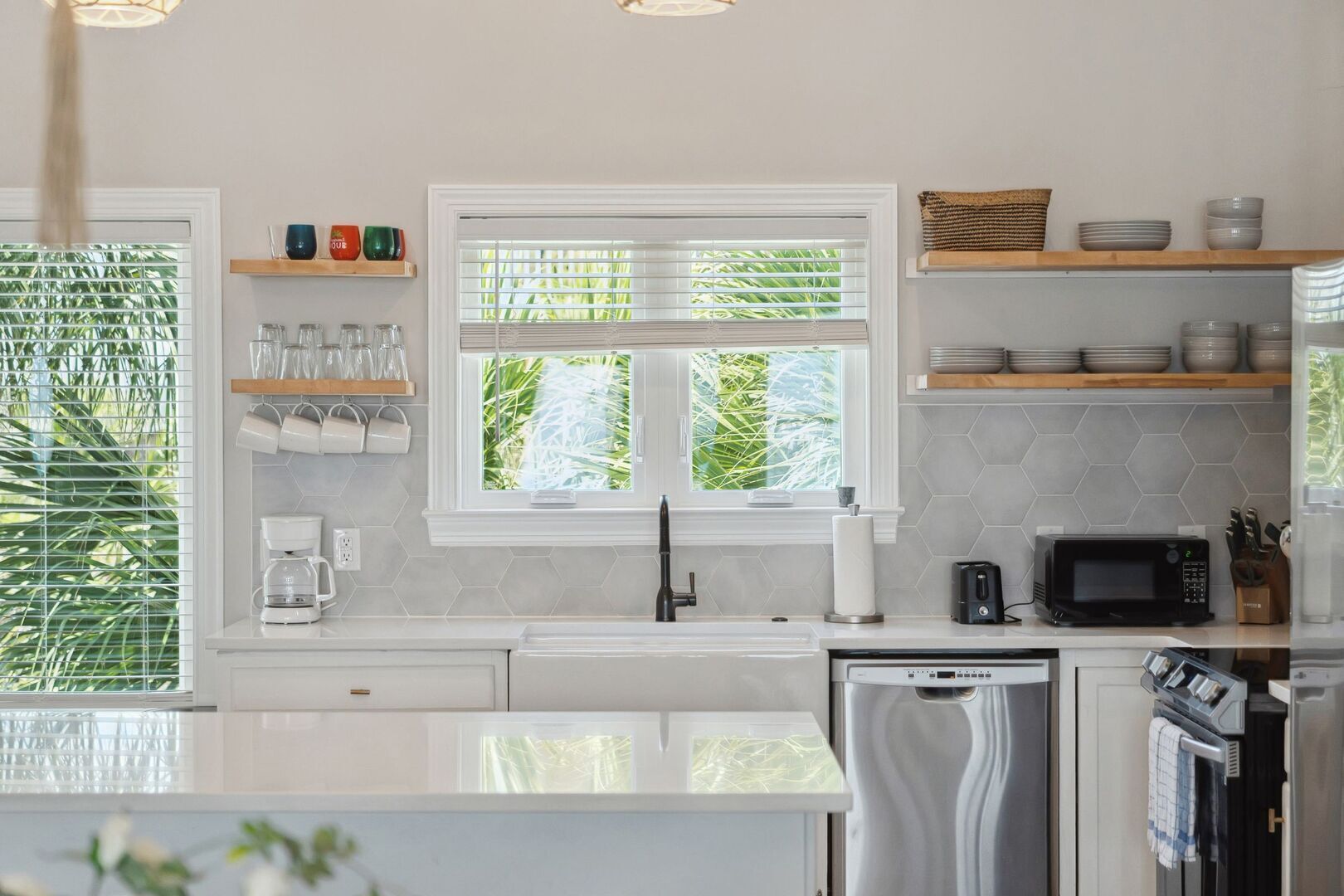 Una cocina moderna con armarios blancos, un microondas integrado y un refrigerador de acero inoxidable.