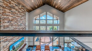 A spacious interior with a high ceiling, large windows offering a view of the outdoors, and a modern seating area.