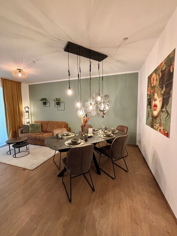 Een eetgedeelte met een tafel voor vier personen, omringd door vier stoelen, een bank en een salontafel.
