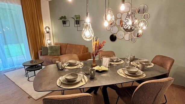 A dining area with a round table set for four, surrounded by upholstered chairs.